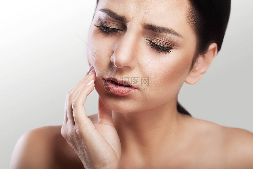 美丽的年轻女子患有灰色背景的牙痛龋齿牙齿问题脸上的痛苦感觉图片