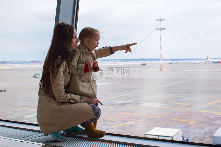 妈和小女儿在机场航站楼望着窗外图片