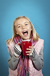 小女孩从红色杯子里喝水时微笑与蓝色隔离图片