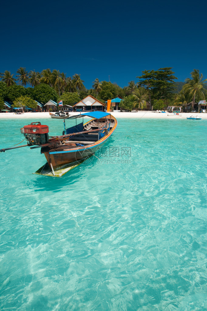 漂浮在完美水晶般清澈的蔚蓝海水中的传统泰国长尾船的特写镜头图片