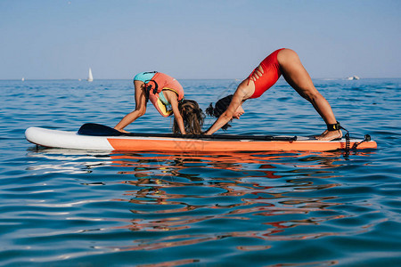 妈和小女儿在海上的桨板上做瑜伽图片