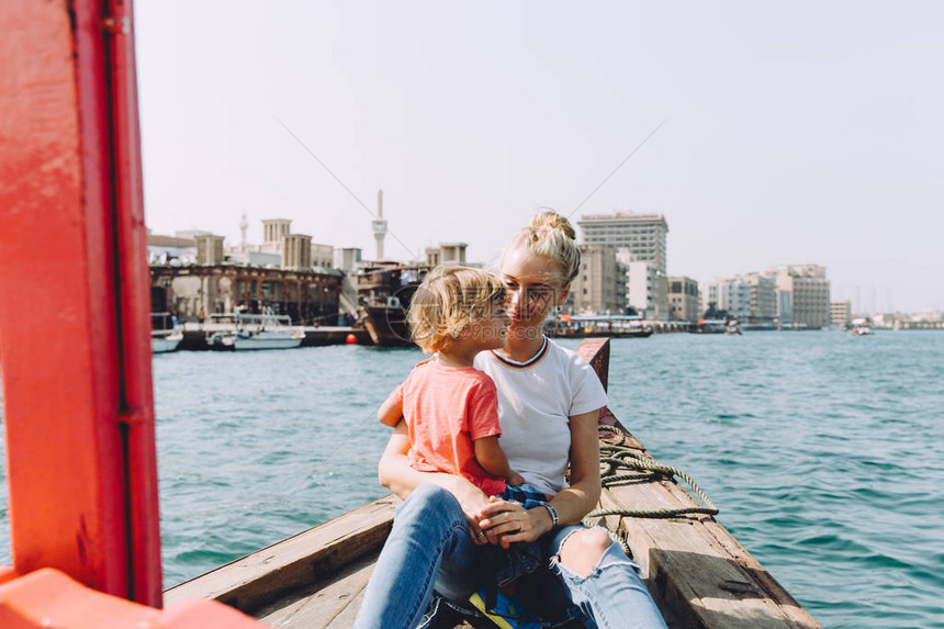 美丽的年轻女子与她的儿子坐在船上思考图片