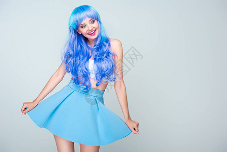 带着明亮蓝头发和裙子的笑着年轻女子在图片