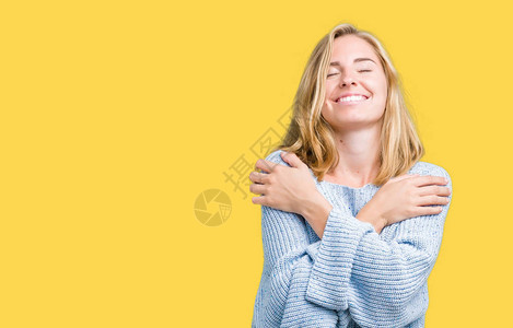 美丽的年轻女子穿着蓝色毛衣在孤立的下拥抱自己快乐和积极图片