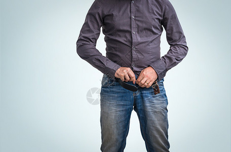 男人在蓝色背景上撒尿后拉上裤子拉链图片