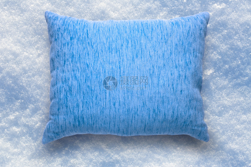 在雪背景的软空白的蓝色枕头图片