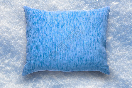 在雪背景的软空白的蓝色枕头背景图片