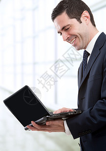 穿蓝西装的帅气年轻商人拿着笔记本电脑图片