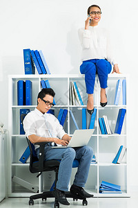 办公室工作人员的垂直图像坐在椅子上的男人和坐在橱柜里图片