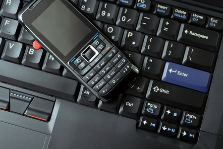 黑笔记本电脑键盘上的无线和清洁移动电话作为一种图片