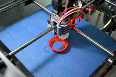 工作3d打印机关闭在蓝色背景上打印3D打印机对象橙色塑料塑料丝图片