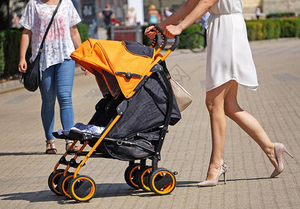 女人推着婴儿车走在街上图片