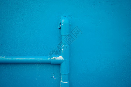 最小化风格蓝墙纹理背景上的蓝色水管古图片