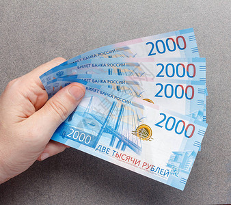 以2000卢布标价的俄罗斯新钞票在雄手中贴在灰色背景上背景图片
