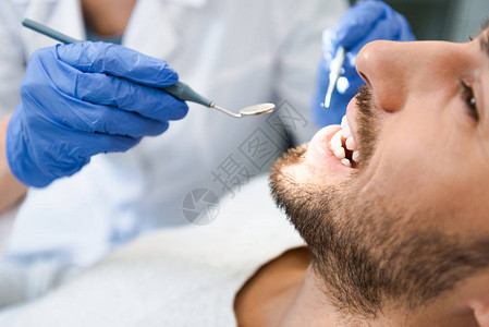 牙科医生检查英俊笑容客户的图片