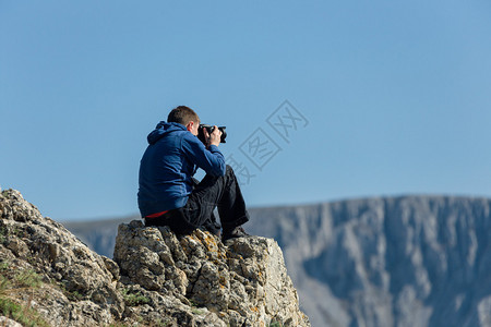 用数码相机在山顶上的业余摄影师图片