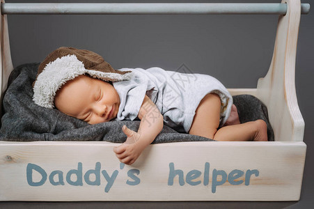 可爱的婴儿宝在睡木工具箱中时露出拇指与高清图片