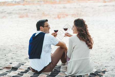 一对夫妇的后视图带着几杯红酒躺在沙图片