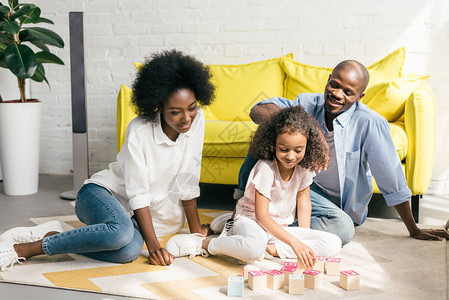 非裔美国父母和女儿在家里的地板上玩木砖图片