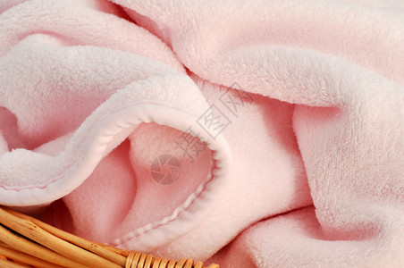 全框柳条篮中柔软的粉色婴儿毯图片