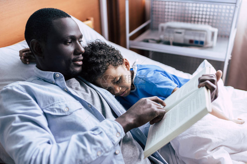 AfricanAmerican父亲对诊所儿子阅读图片