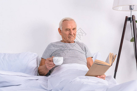 老人肖像家里床上有一杯咖啡阅高清图片