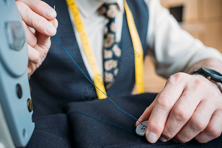 缝纫车间缝制纫按钮至深蓝色夹克的裁缝图片