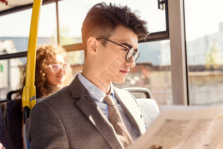 公共交通中男阅读报纸有选择重心在背景图片
