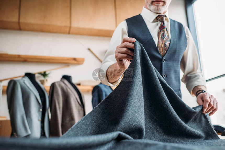 在缝纫车间用灰色布裁剪时尚成熟裁缝的镜头图片
