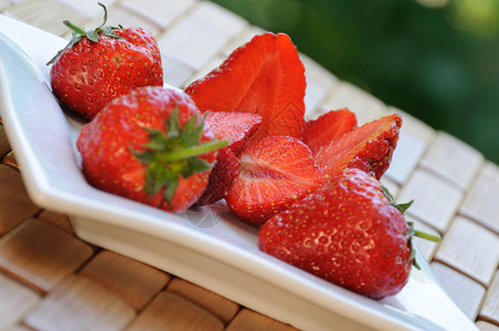 将新鲜草莓切片放在盘子上特写图片