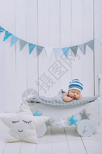 顶着帽子的可爱新生婴儿睡在木头婴儿床上图片