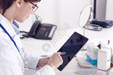 医生或护士使用平板电脑研究医疗信息或在医院或诊所的办公室图片