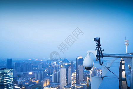 闭路电视监控安保摄像头在黄昏时带着城背景图片