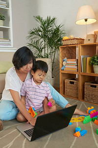 亚洲母亲和儿子坐在地板上在电脑上图片