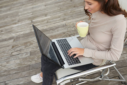 年轻女士在计算机工作时喝着咖啡图片