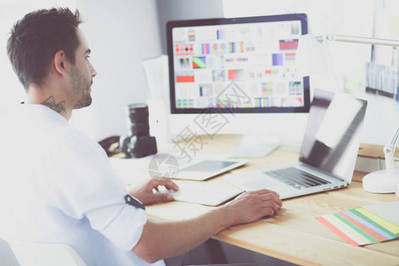 年轻设计师在线工作时坐在笔记本电脑和电脑前的图形背景图片