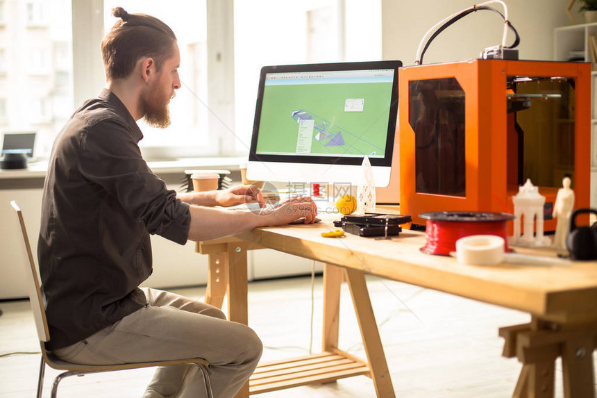 自信的胡须设计师使用计算机程序在3D打印机的帮助下创建原型的剖面图图片