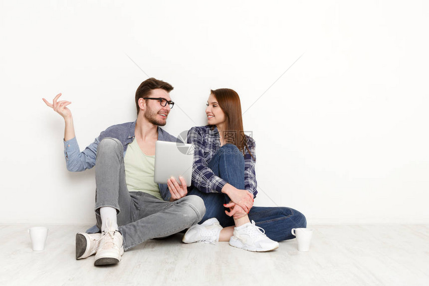 夫妇手拿平板电脑讨论一些事情快乐的男人和女人坐在新公寓白色图片
