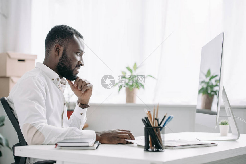 在办公室电脑上工作的英俊的非裔美国商图片
