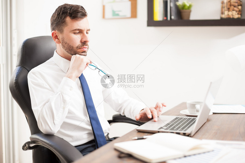 长着胡子的帅气年轻男子在笔记本电脑上工作图片
