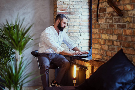 时髦的留胡子雄用笔记本电脑在有阁图片