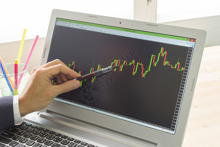 商人正在指向股票图或前方图用笔进行专业贸易员的技术分析图片
