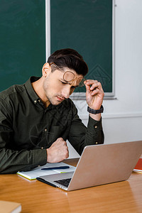 在课堂办公桌用笔记本电脑戴眼镜的男图片