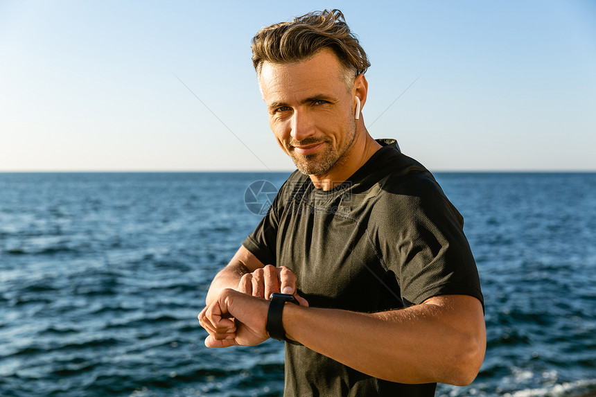 在海边戴无线耳机和智能手表的图片