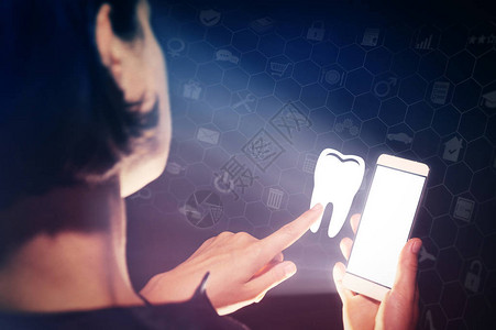 一个女孩手里拿着智能手机的形象她按下牙齿图标搜索牙医牙图片
