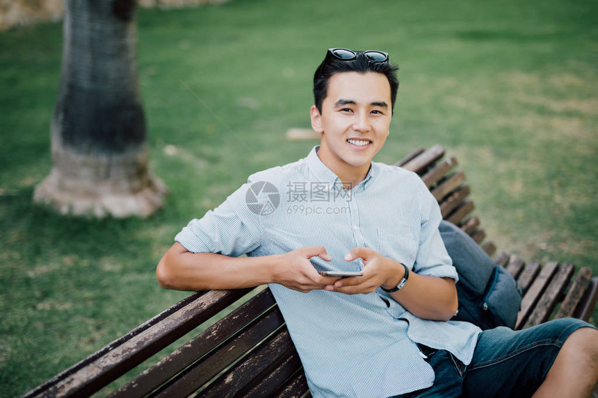 年轻人坐在公园的长椅上图片