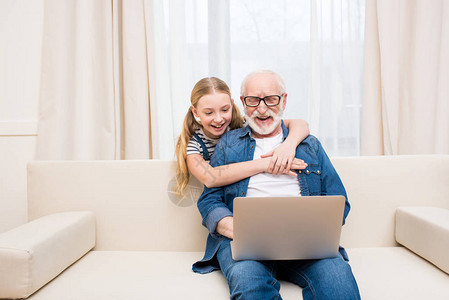 在家里用笔记本电脑拥抱快乐祖父图片