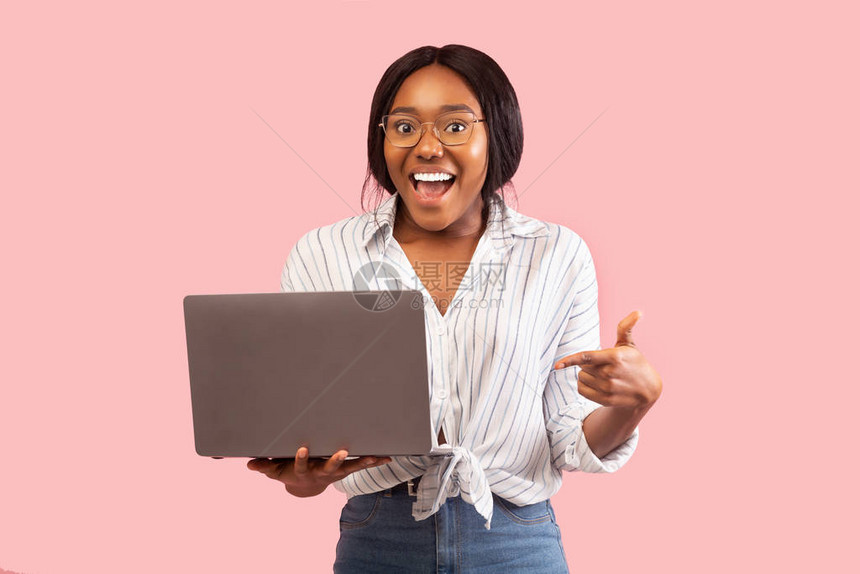 极感兴奋的非裔美国女士持有笔记式指针建议网站立在粉红背景上图片