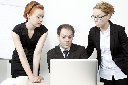 由两名妇女和一名男子组成的令人惊讶的商业团队聚集在一台笔记本电脑周围图片