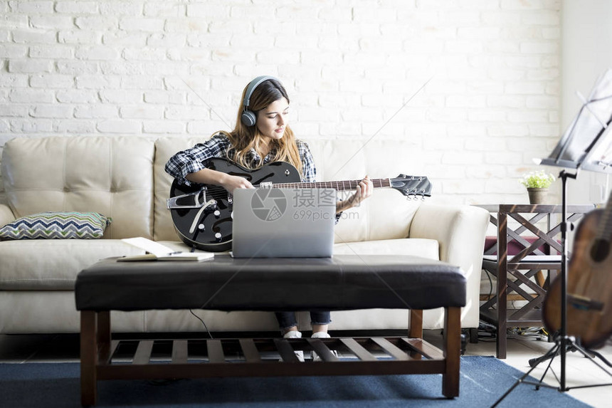 有创意的年轻caucasian女人与吉他创作一首新歌并录入她图片